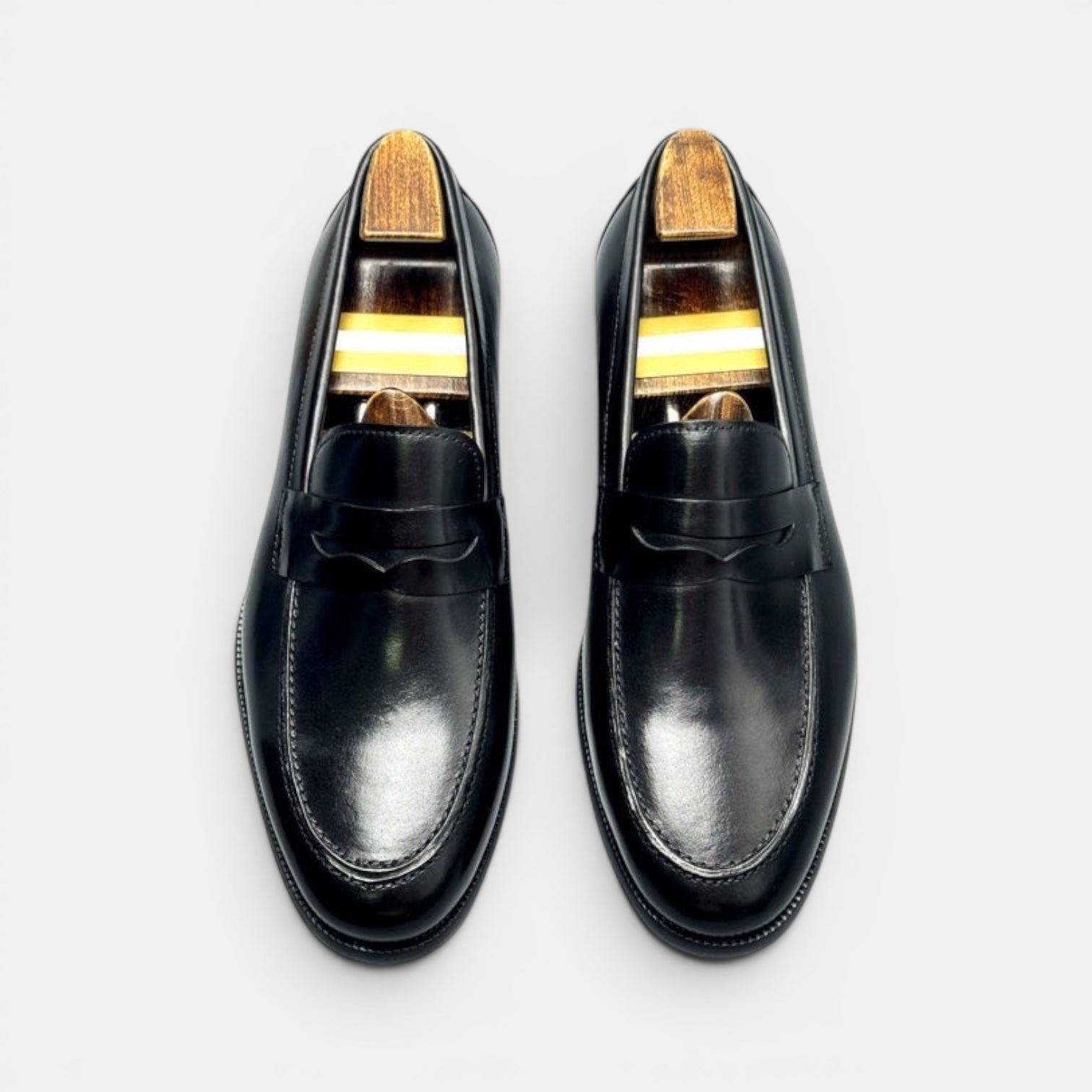 Barcon Getta Inc BANGUI black polished leather penny loafers with strap detail and shoe trees.