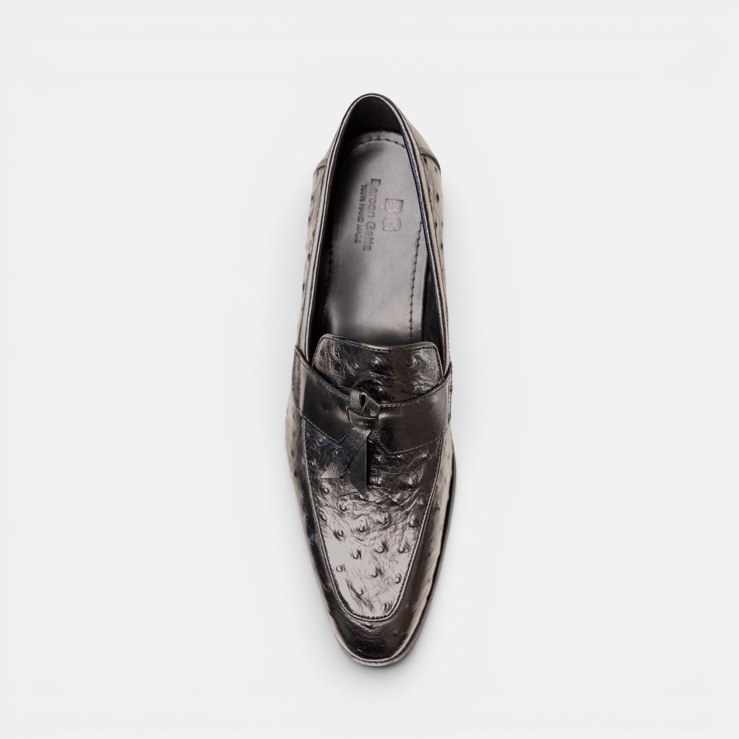 Barcon Getta Inc black ostrich-embossed leather kiltie tassel loafer with pointed toe and stacked heel.