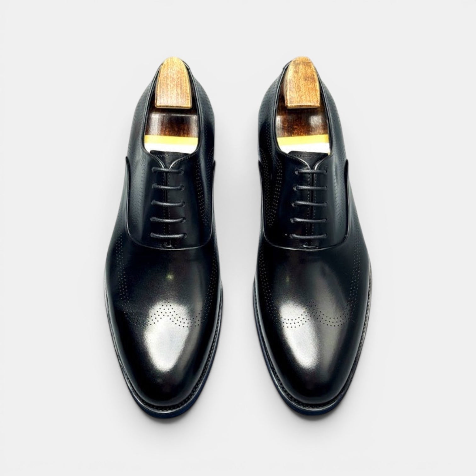 Barcon Getta Inc black leather wingtip brogue Oxford dress shoes with medallion toe perforations and wood shoe trees.
