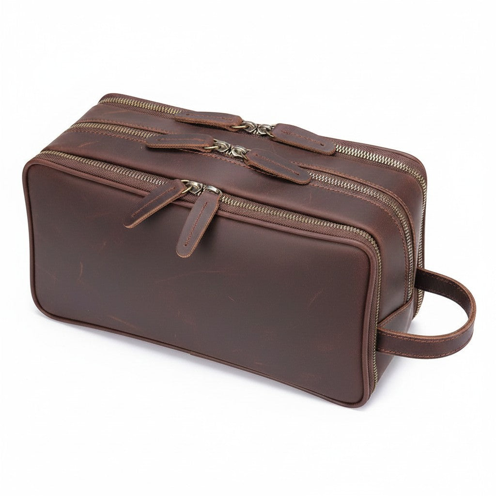 Barcon Getta Inc brown leather travel toiletry bag with three zippered compartments and a side handle.