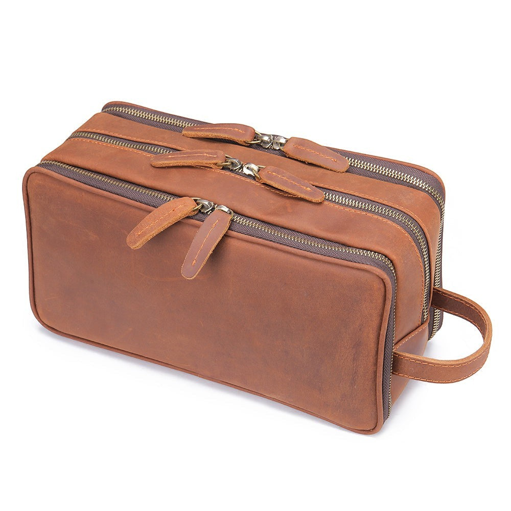 Barcon Getta Inc brown leather travel toiletry bag with three zippered compartments and a side handle.