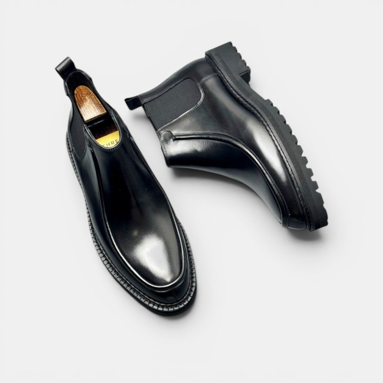 Barcon Getta Inc black leather Chelsea boots with squared toe and lug sole. Elastic side panels for slip-on fit.