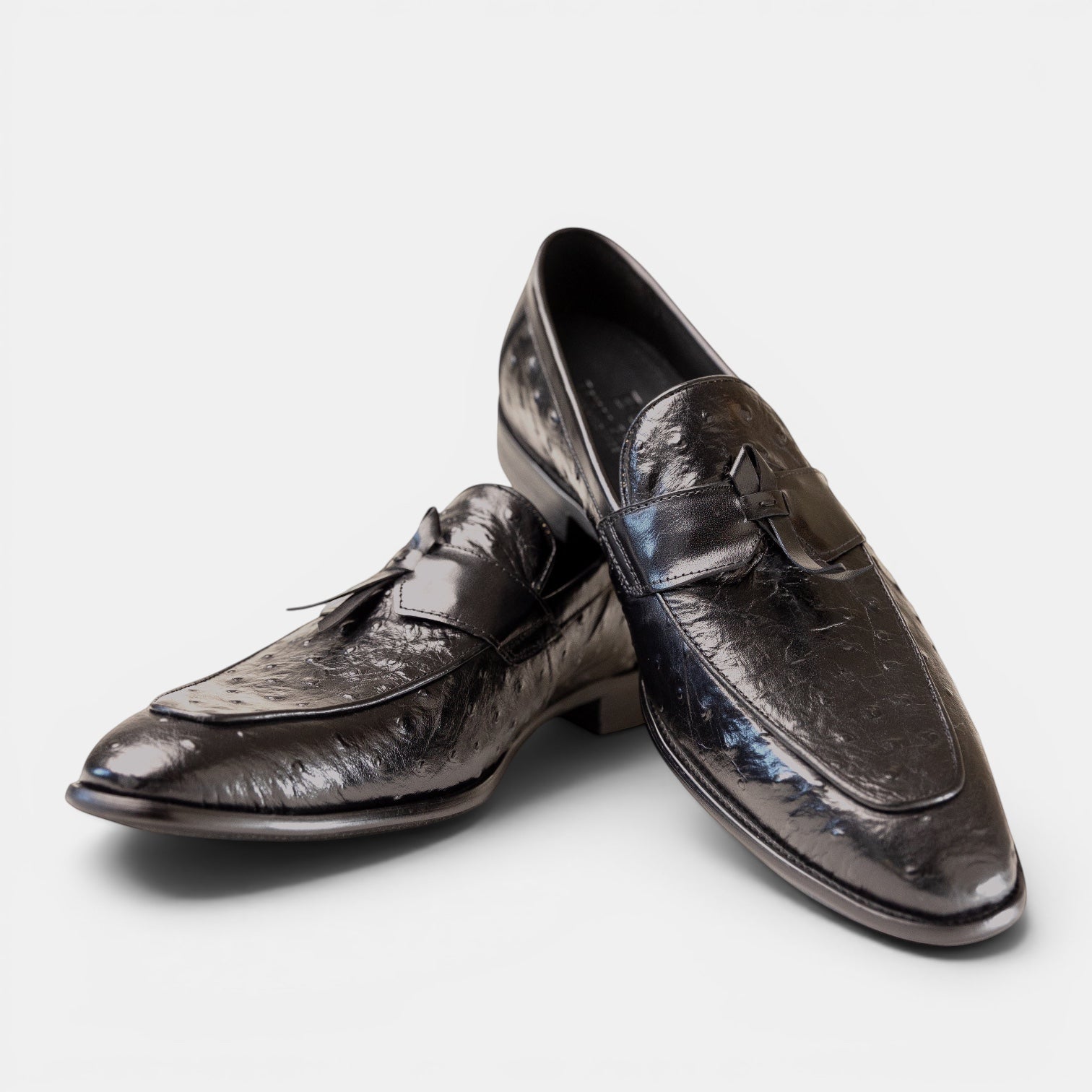 Barcon Getta Inc black ostrich-embossed leather kiltie tassel loafers with a pointed toe and stacked heel.