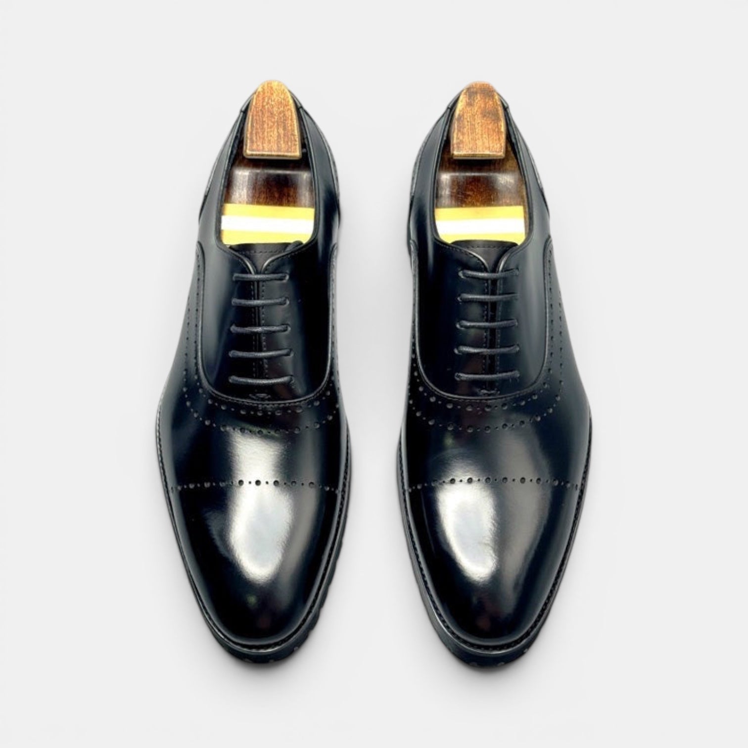 Barcon Getta Inc BANJUL black full grain leather wingtip Oxford dress shoes with medallion toe perforations and lug sole.