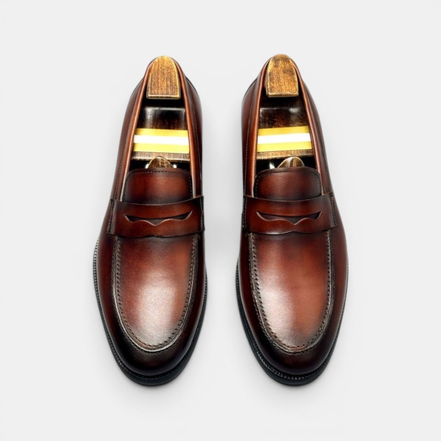 Barcon Getta Inc BANGUI brown polished leather penny loafers with strap detail and wooden shoe trees.