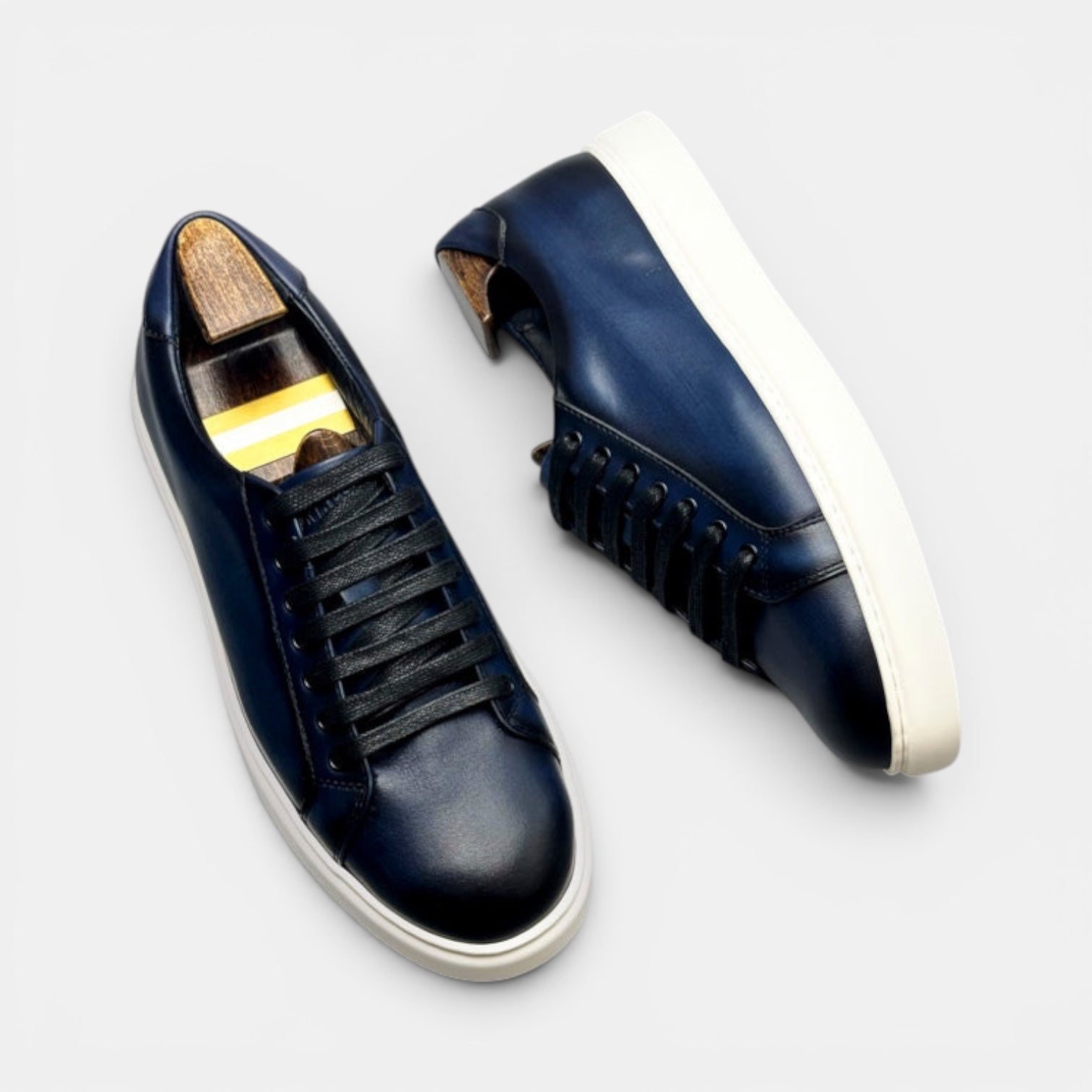 Barcon Getta Inc MEDA LOW TOP hand-burnished deep navy leather sneakers with white soles and black laces.